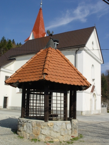 Vodnjak in v ozadju cerkev Sv. Urha in Martina na Zaplani.